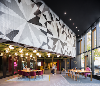 A 1980s-era office building in Denver’s historic Colfax Avenue District gets a new look and identity, courtesy of Artaic. Designed by Gensler, The Amp’s newly designed glass facade gives pedestrians and onlookers a view of its eclectic interiors, marked by an expansive, eye-catching mosaic mural that dominates the building lobby.